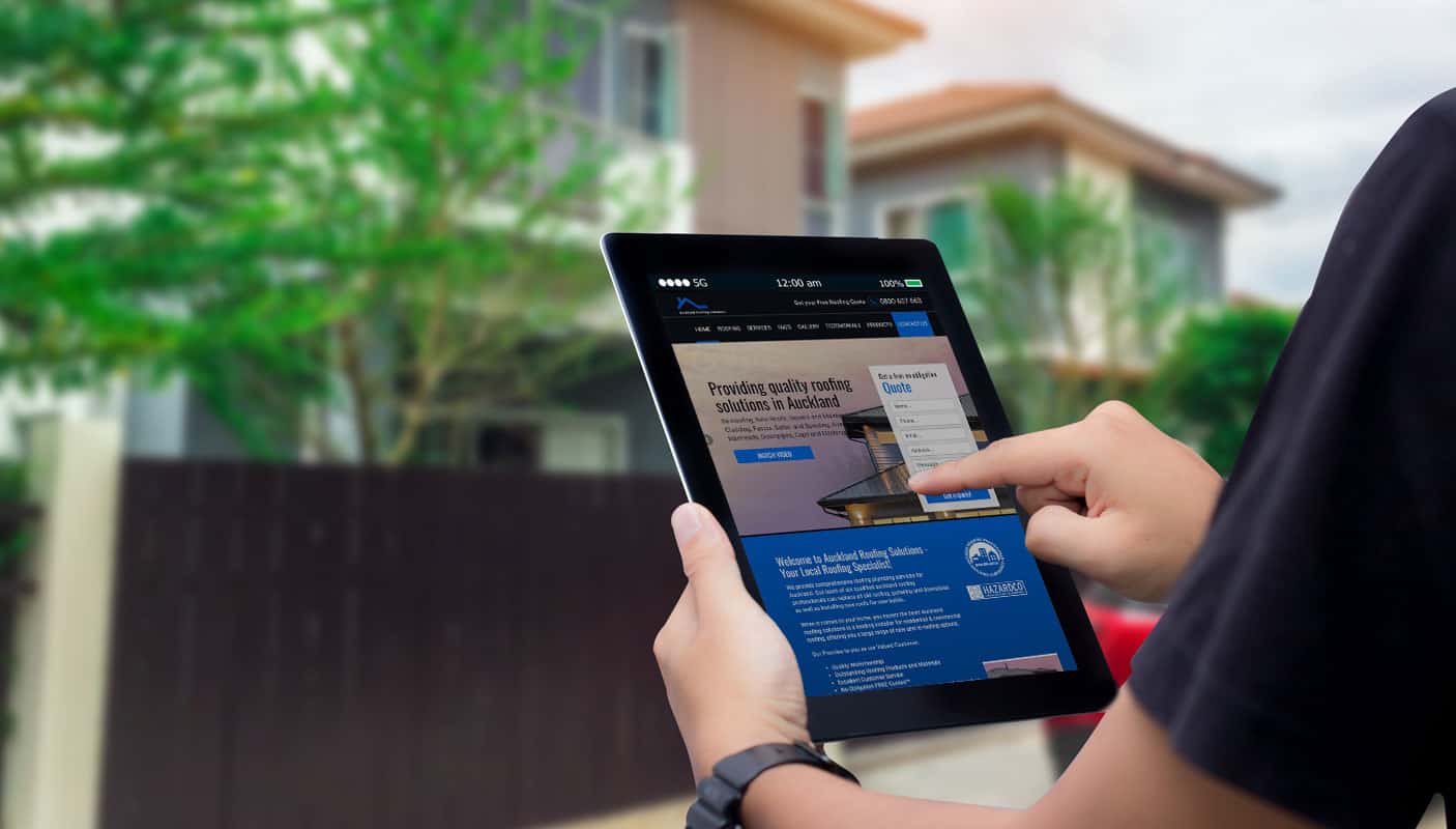 A man standing outside a house browsing a small business trade website and clicking on the Get A Quote form